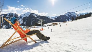 A skier relaxing in a chair on a sunny day