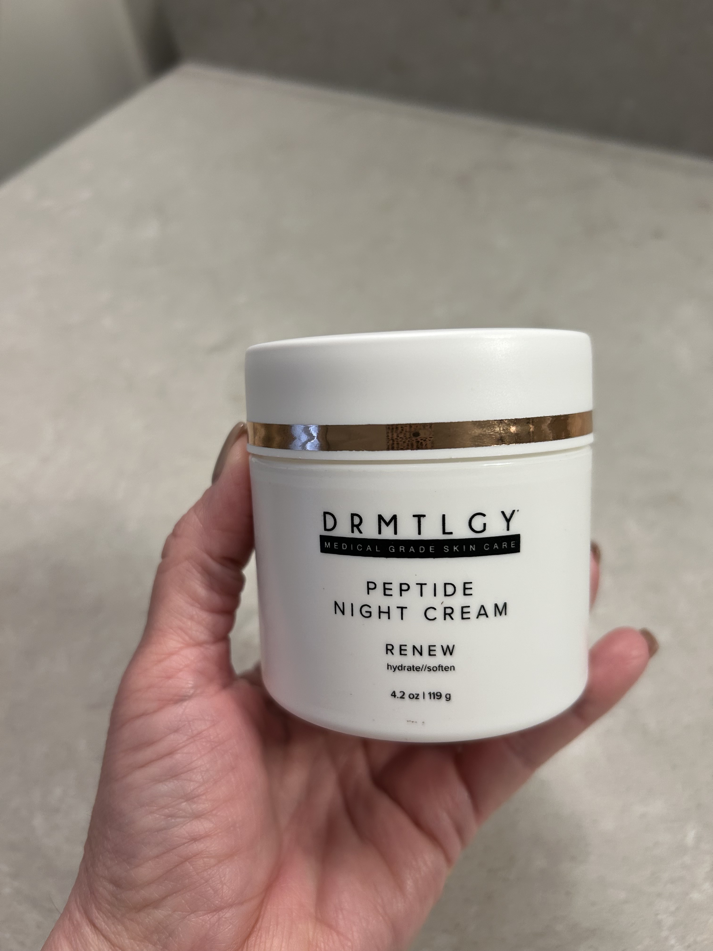 An image of Lori Brascia holding the Drmtlgy Peptide Night Cream.