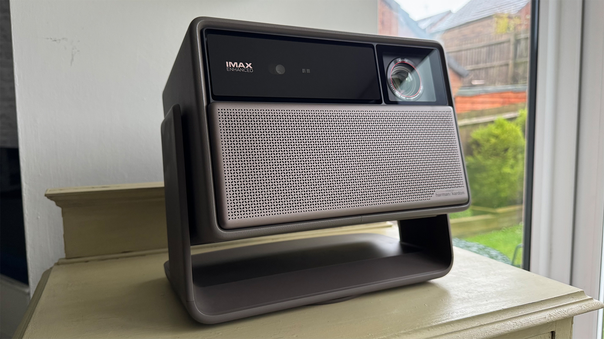 Xgimi Horizon 20 Max home cinema projector on wooden furniture next to window, projector is angled slightly on stand