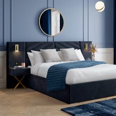 A blue-themed bedroom with blue paneled walls, a dark blue bedframe and side tables