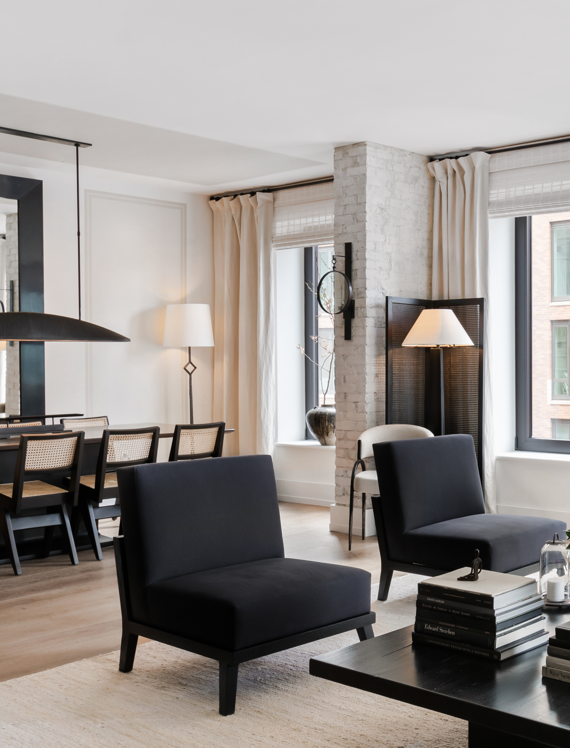 A large open plan living/dining area with a dining table, two black armchairs, and a coffee table