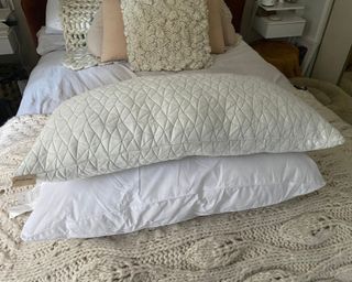 Two pillows sitting on bed on chunky knit throw