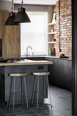 A small kitchen with exposed brick walls and black cabinets