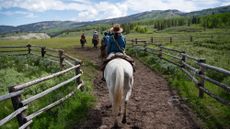 Darwin Ranch guests ride horses down a trail on the property
