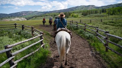 Darwin Ranch guests ride horses down a trail on the property