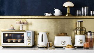 Breville's brass accent kitchen appliances range in a blue and brass kitchen