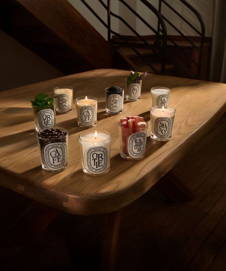 Diptyque relaunch candles on a pale wooden table