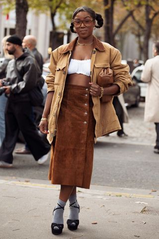 A guest wearing a barn jacket and suede skirt at Miu Miu SS25