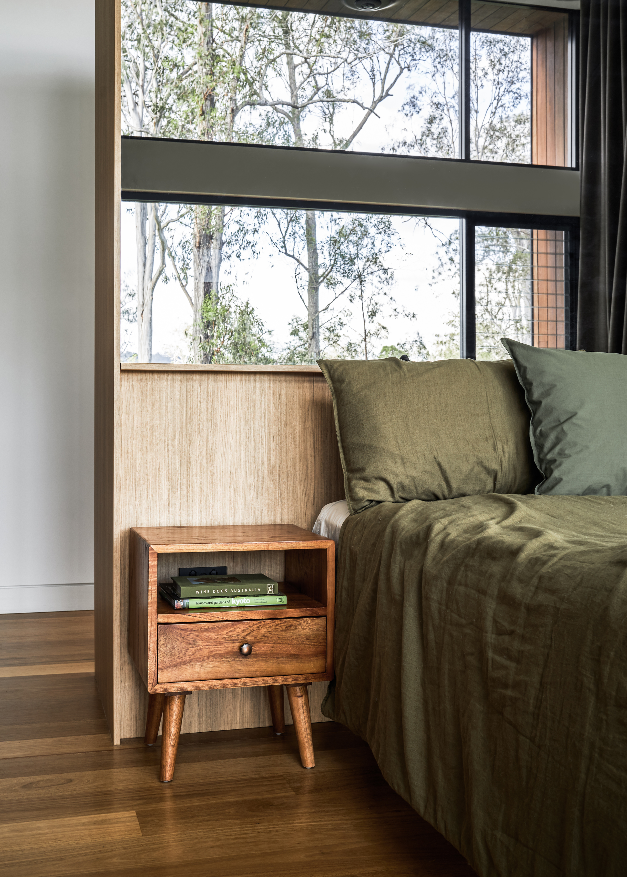 A bedroom with a green bedscape and a wood nightstand