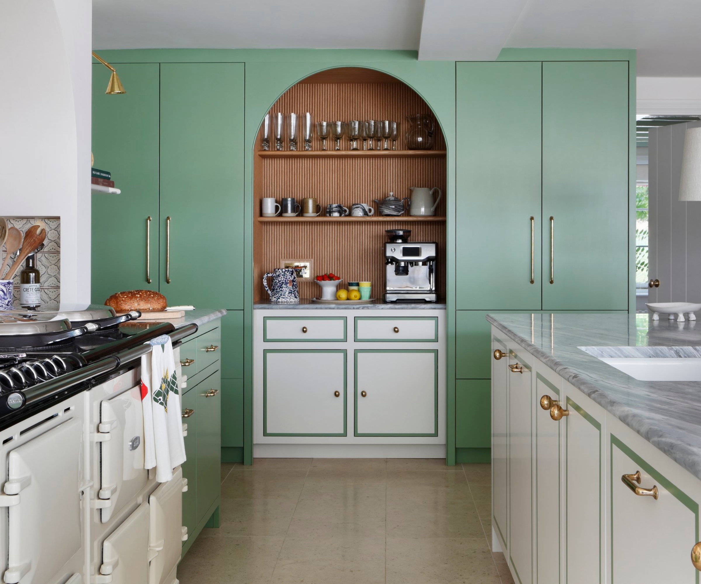 An open plan kitchen with green full length cabinets, and white perimeter cabinets with a green border