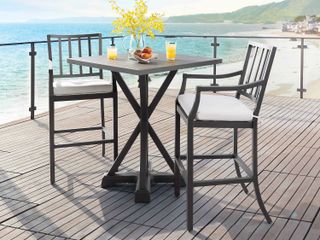 High chairs and a round table on a balcony overlooking the ocean
