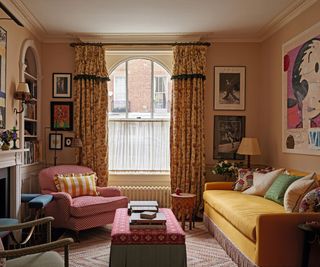 sitting room with patterned curtains and yellow sofa with frill trim and pink patterned accent chair and red patterned ottoman and pale pink painted walls