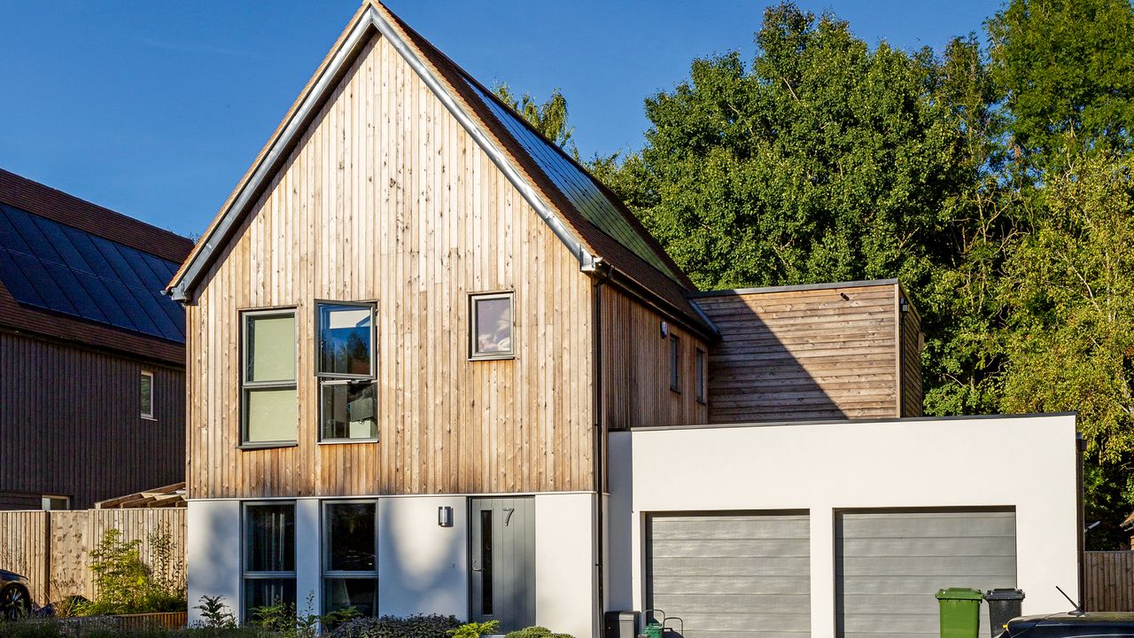 Front of house with white and wooden cladding and double garage