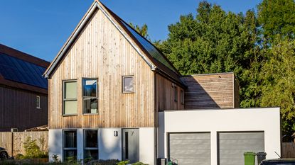 Front of house with white and wooden cladding and double garage