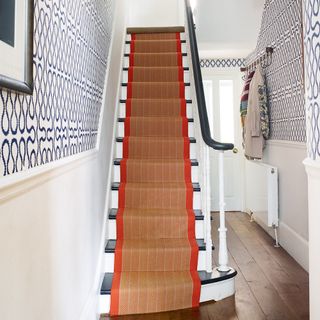 white and blue hallway with wallpaper above dado rail and red trim stair runner