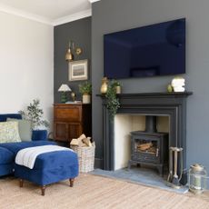 A living room with a blue sofa and a TV over the fireplace