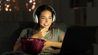 woman watching online tv in the night sitting on a couch in the living room at home