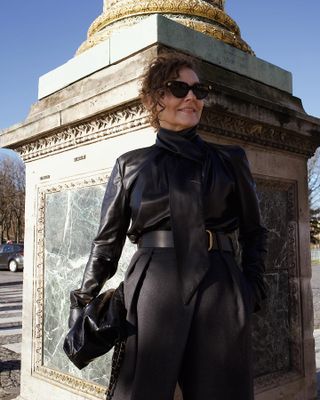 woman wearing a black outfit with a leather top and tailored trousers