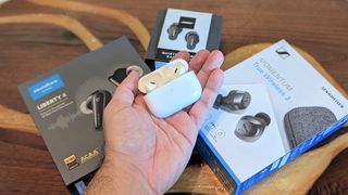 Apple AirPods Por 2 in hand with packaging boxes from other brands in background