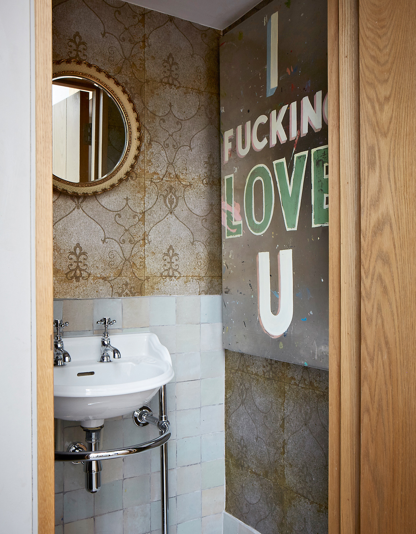 Small bathroom with mismatching bathroom tiles and large artwork
