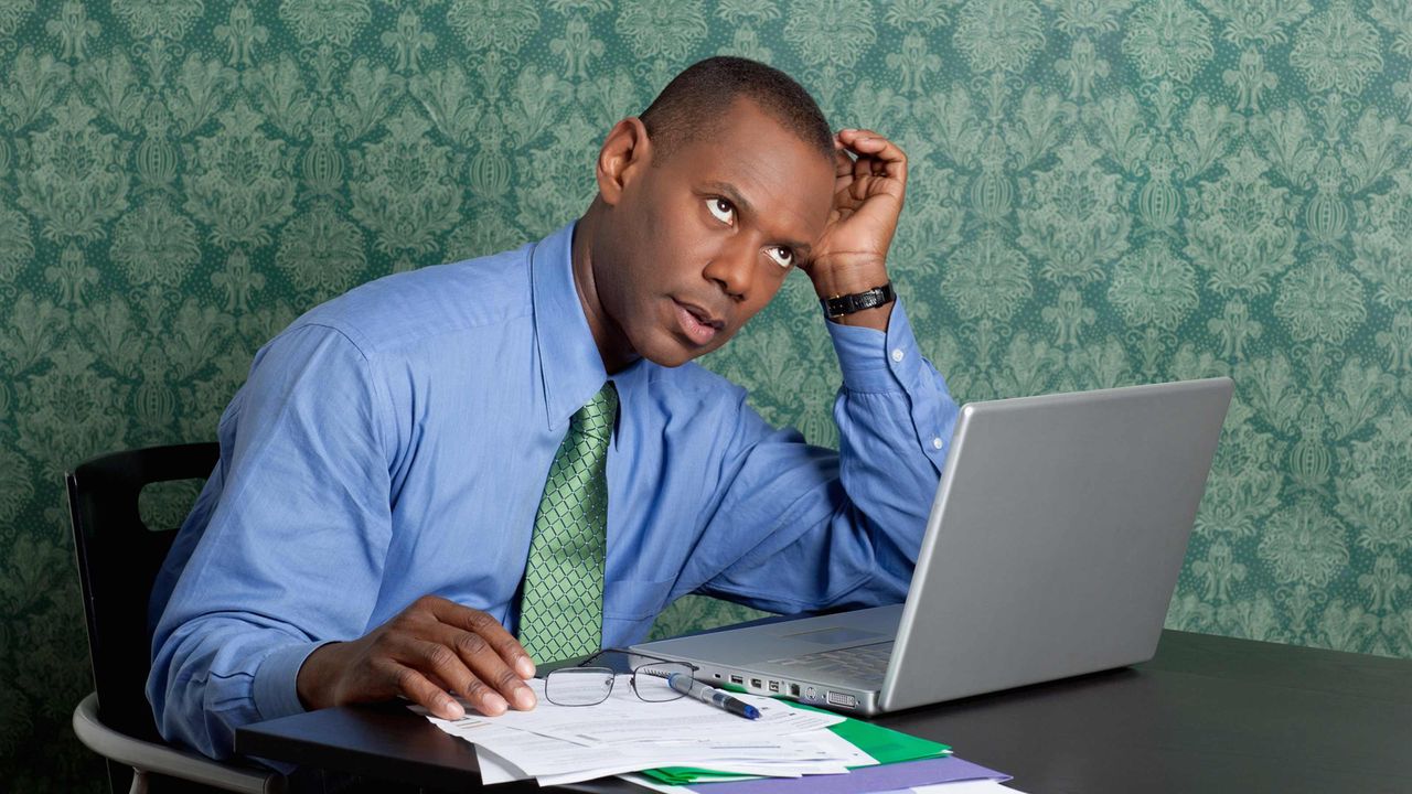 A man sitting at a laptop computer rolls his eyes.