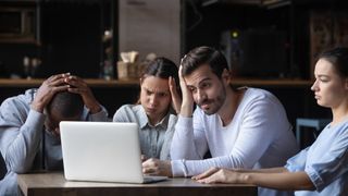 Windows 10 users looking confused around a laptop