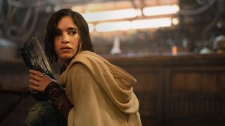 Sofia Boutella's Kora clutches a gun as she looks behind her in Rebel Moon