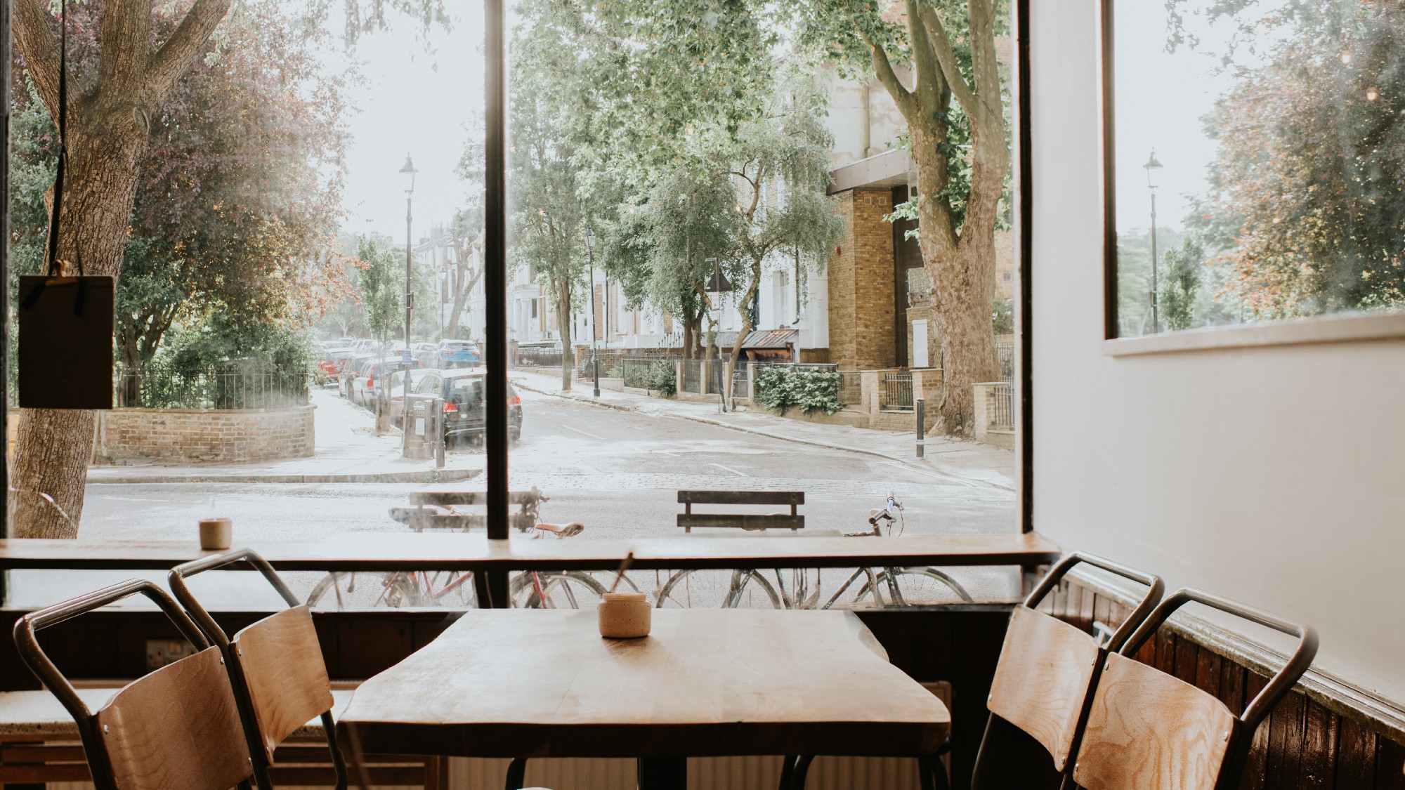 view of a restaurant table near a window. no one is seated. there are lush trees outside the window