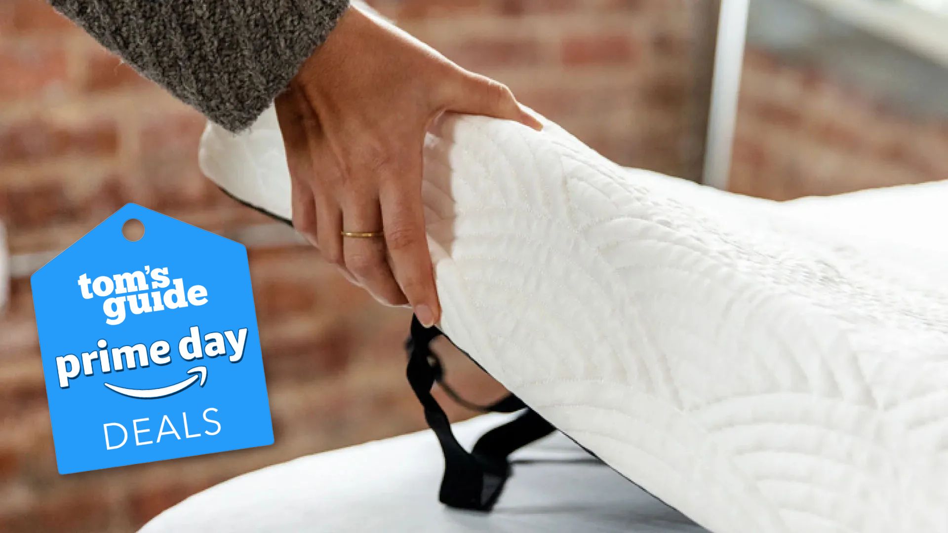 A woman&#039;s hand places the ViscoSoft Active Cooling Copper Mattress Topper on top of a bed. A Prime Day deals badge is in the foreground. 