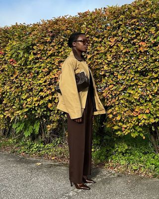 @chrystelleeriksberger wears a barn jacket with brown tailored trousers and heels