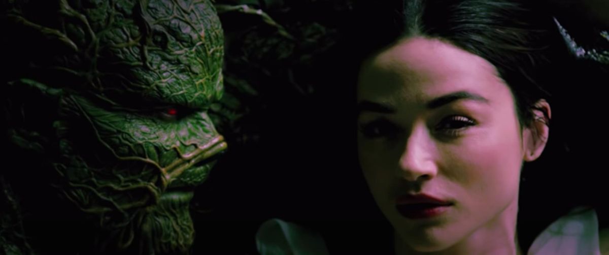 A slimy green monster known as Swamp Thing looks longingly at a beautiful sultry woman 