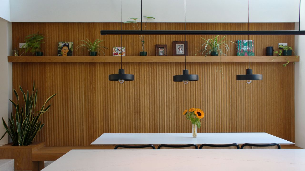 Wood panelled kitchen wall with black lighting and white kitchen table