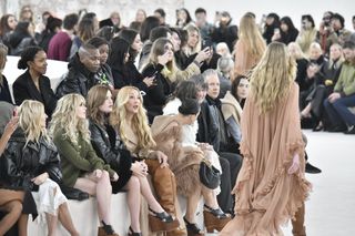 a model walks the runway at chloe in front of a row of women wearing boho outfits.