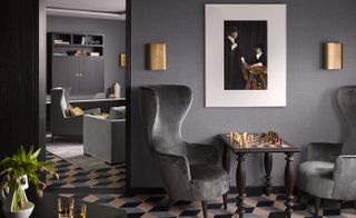 Grey seating area featuring wingback chairs, wooden coffee table with chess set, and geometric floor tiles