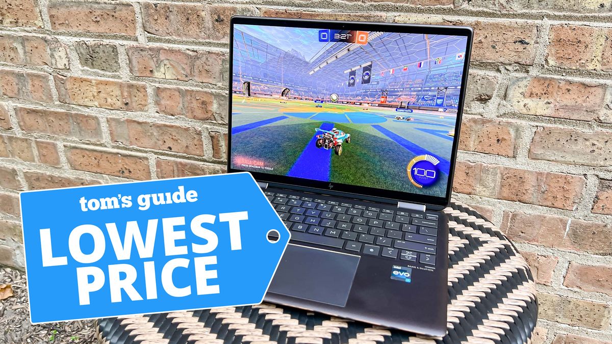 HP Spectre x360 shown on table against a brick wall displaying a video game