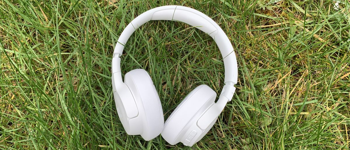 the jbl tune 750btnc headphones in white pictured on a grass background