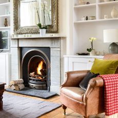 White living room with an gas fireplace and cabinets around the chimney, wooden flooring, and a leather armchair