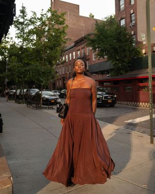 @cocobassey wearing a brown strapless maxi dress