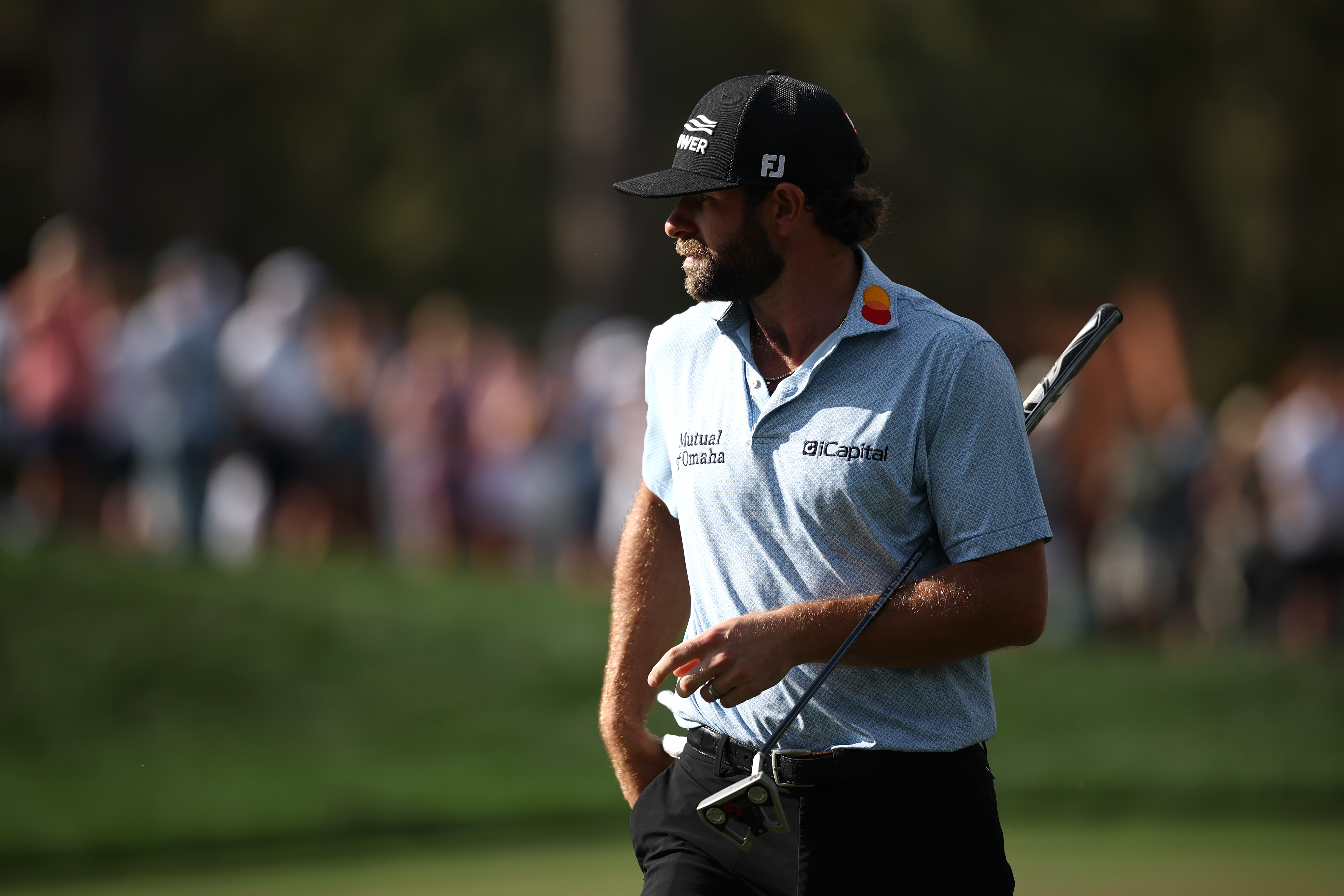 Cameron Young walks off the green holding his putter