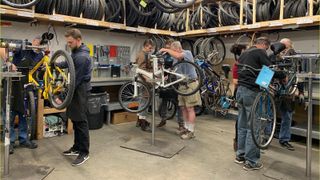 Three people working on bikes in a workshop