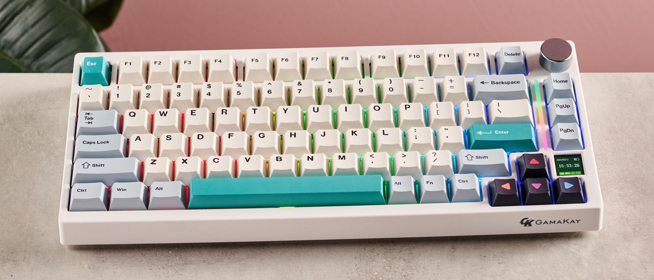 Gamakay TK75 V2 on desk with pink wall and plant in background