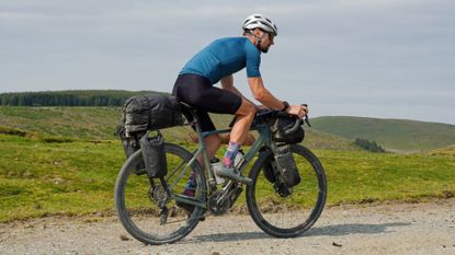 Male cyclist riding a gravel bike with bikepacking bags