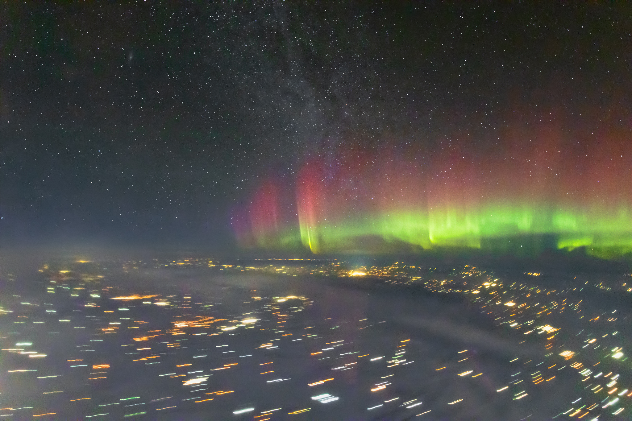 A photograph taken by pilot Ralf Rohner of the aurora with blurred city lights on the ground
