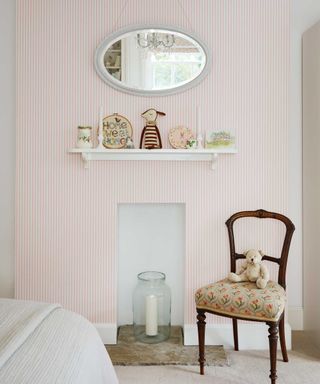 striped wallpaper and a small fireplace with chair beside in childrens bedrom