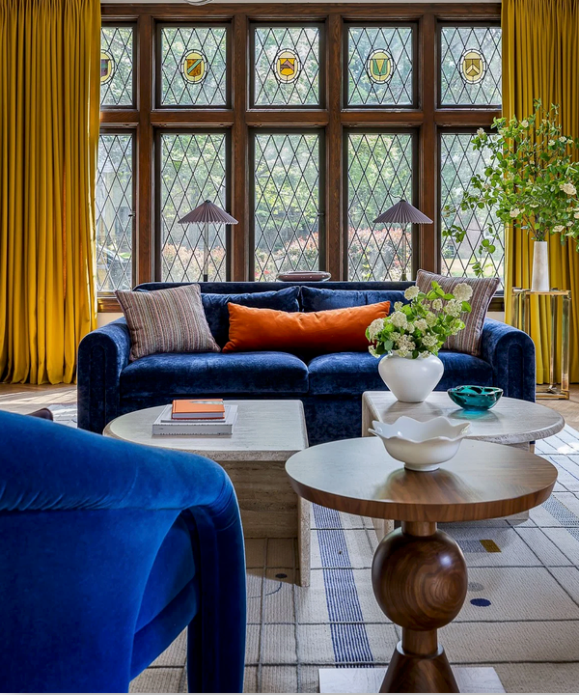 Bright blue velvet sofa in living room with bright yellow curtains