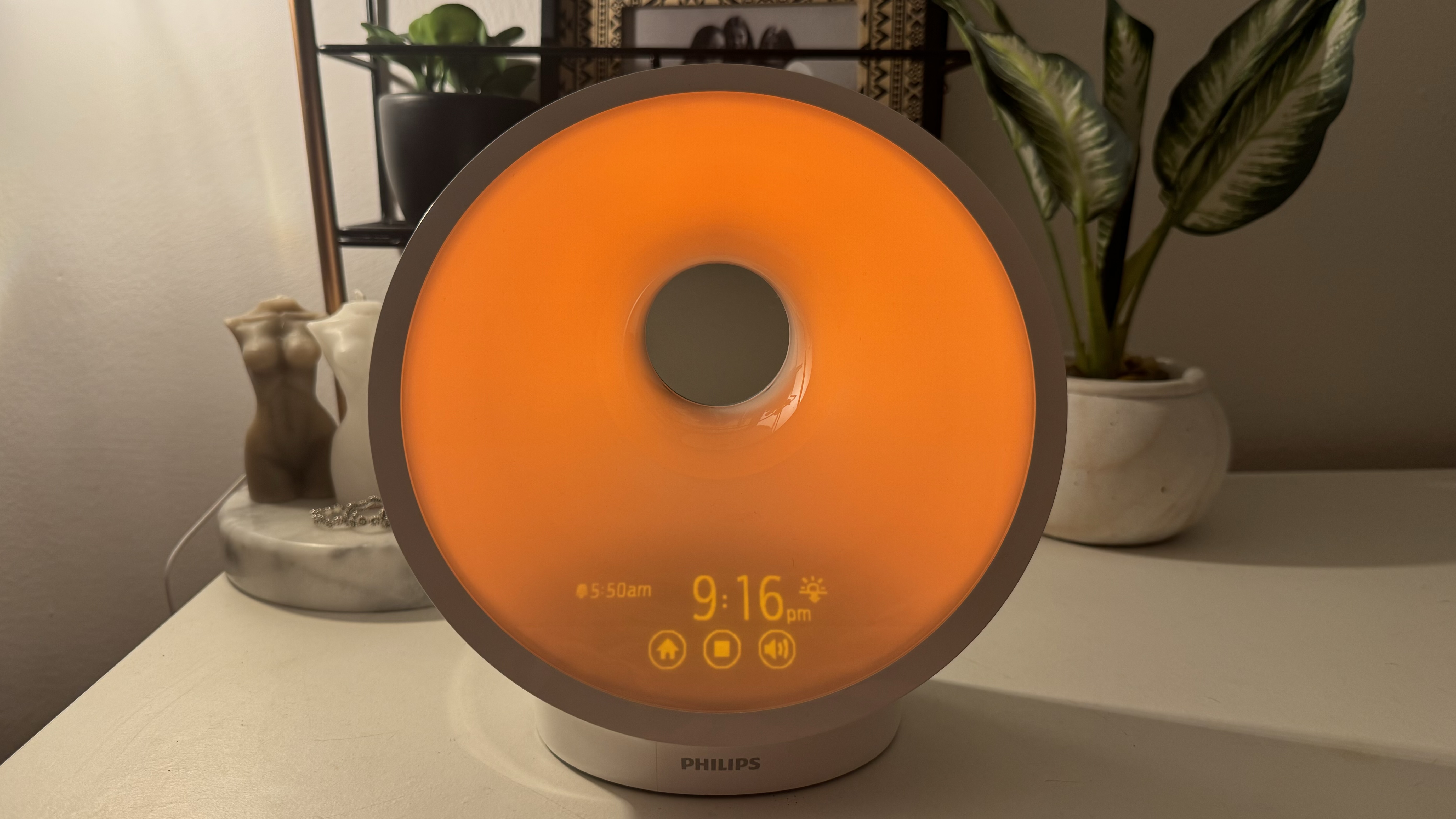 Philips SmartSleep HF3651 wake-up light on bedside with plants and candles.