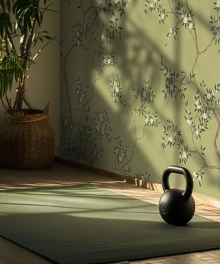 A green yoga mat on a light wood floor with a black kettle bell weight on top. A green wallpapered wall.