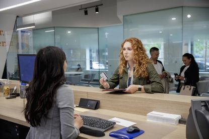 client with debit card talking with bank teller in bank