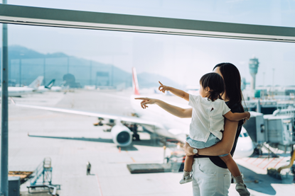 Woman and child pointing out of the window at the airport as lockdown travel rules change