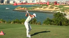 Rory McIlroy on the tee playing the par-3 17th hole which requires a tee shot over the Arabian Gulf to an elevated green